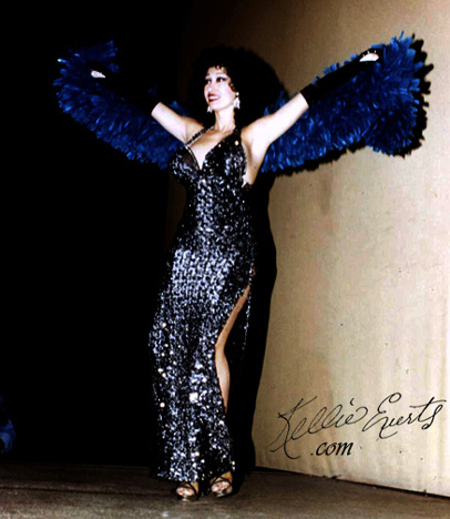 Stripping on stage in sequines and grand blue feather boa. Big tits inside glistening silver scaled gown.