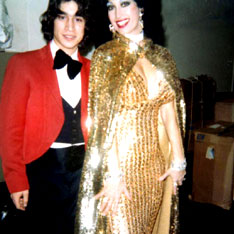 Magnificent stripper in glistening, golden fish scale gown and glitter cape posing for photo with theatre usher before perfomance